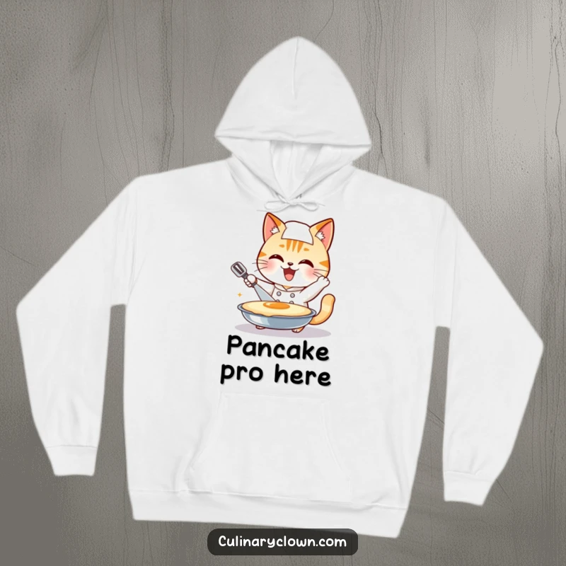 Funny smiling cat chef character attempting a giant pancake flip, featured on a soft hoodie, a great funny gift.